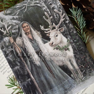 May include: A rectangular art print featuring an illustration of an elderly person with long white hair wearing a dark hooded cloak and holding a wooden staff, standing beside a white reindeer with a wreath, with text reading mary feywood art by maartje van dokkum.