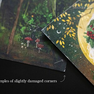 May include: Two examples of slightly damaged corners on printed cards. The first card shows a forest scene with mushrooms and a tree trunk. The second card shows a woman with a wreath of holly and berries on her head. The text "Maartje van Dokkum" is visible in the upper right corner of the second card.