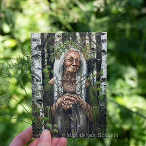 Pode incluir: Uma pintura de uma mulher mais velha com cabelo branco comprido usando uma t&uacute;nica verde e uma coroa de folhas. Ela est&aacute; com as m&atilde;os juntas no colo. Um corvo preto est&aacute; empoleirado em um galho atr&aacute;s dela. O fundo &eacute; uma floresta de b&eacute;tulas. A pintura &eacute; assinada "Maartje van Dokkum".