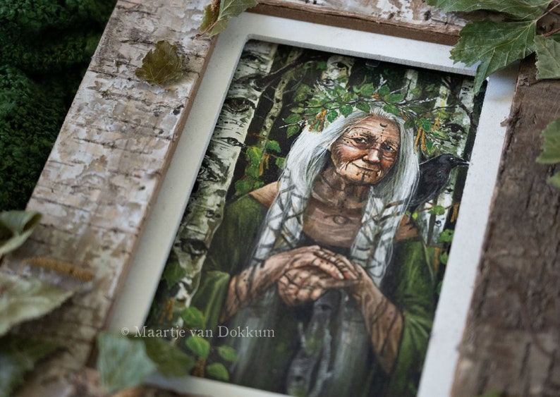Pode incluir: Uma ilustra&ccedil;&atilde;o emoldurada de uma mulher com cabelo branco comprido usando uma coroa de folhas. Ela est&aacute; cercada por um cen&aacute;rio de floresta com b&eacute;tulas e um corvo empoleirado em seu ombro. A obra de arte &eacute; assinada "Maartje van Dokkum".