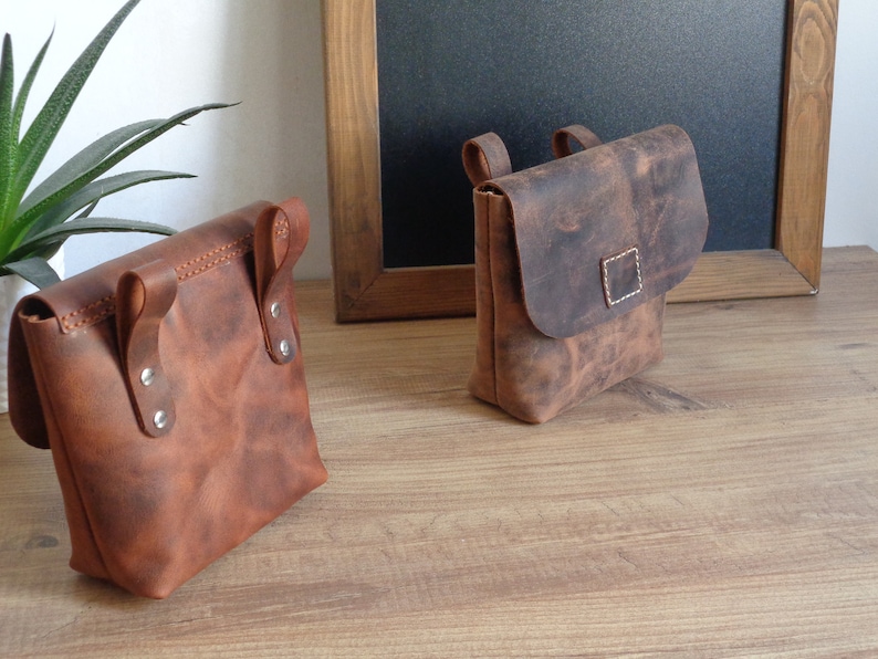 Peut inclure: Deux sacs en cuir marron avec une fermeture &agrave; rabat et une bandouli&egrave;re. Les sacs ont un aspect vieilli et sont faits d'un cuir &eacute;pais et r&eacute;sistant.
