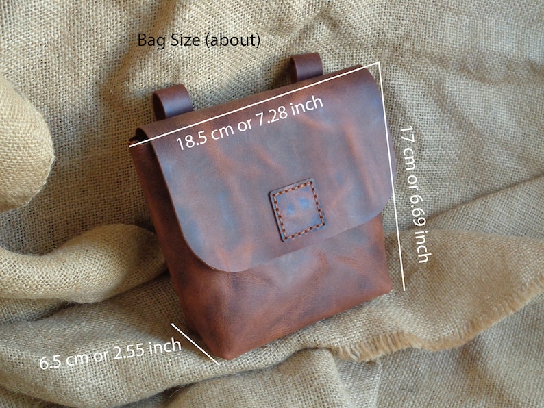 Peut inclure: Un sac en cuir marron avec une fermeture &agrave; rabat et une petite poche carr&eacute;e sur le devant. Le sac mesure 18,5 cm de large, 17 cm de haut et 6,5 cm de profondeur.