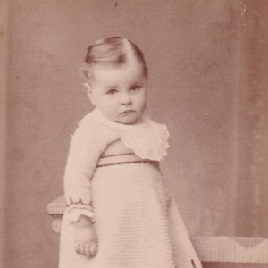 Small portrait photo: Toddler in crocheted dress on bench (Robert Schucht, Zurich, Switzerland)