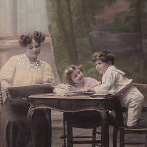 Mutter mit zwei Kindern beim Lernen, glänzende antike deutsche Postkarte, 1910