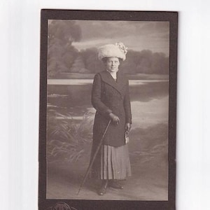 Frau mit Pelzhut und Mantel an Flussufer, deutsches Visitfoto (Hermann Tietz, München), 1910