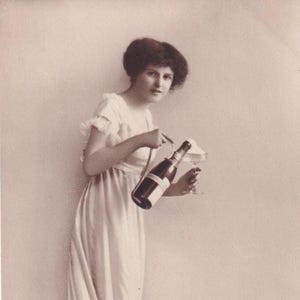 Femme (Wally) avec une bouteille de champagne dans un support et un verre, carte postale allemande ancienne, envoyée en 1918