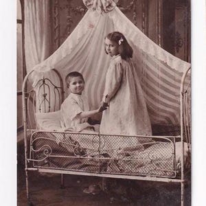 Frères et sœurs dans un lit à baldaquin, carte postale anglaise ancienne, envoyée en 1909