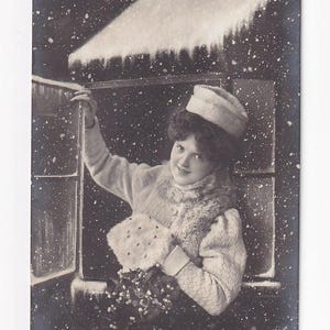 Frau mit Mütze und Muff am Fenster im Schnee, antike deutsche Postkarte, 1909 versendet