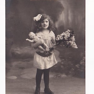 Pareja de postales antiguas: niña con muñeca desnuda