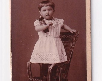 Toddler with sailor doll standing on wicker chair, Carte de Visite from Germany by August Tresselt