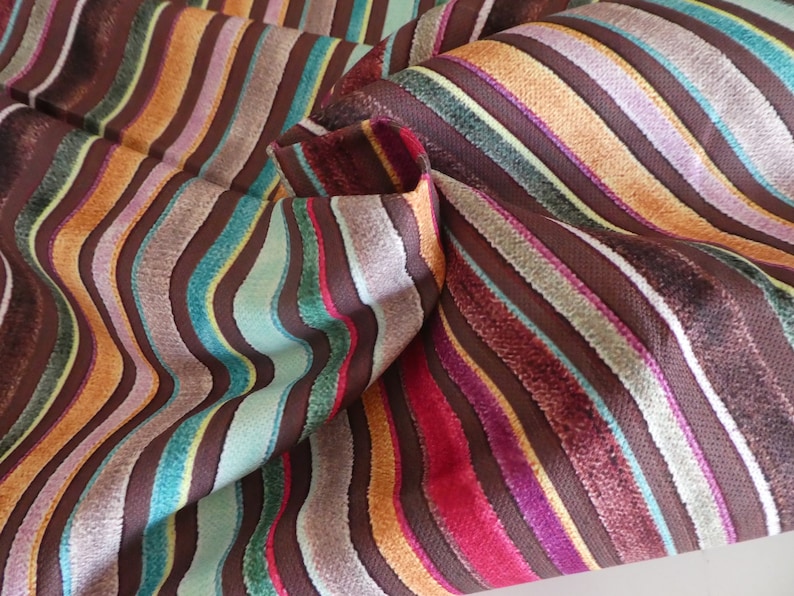 Puede incluir: Tela de rayas multicolores con un patr&oacute;n ondulado. La tela est&aacute; hecha de un material suave y texturizado y presenta una variedad de colores, incluyendo marr&oacute;n, naranja, azul verdoso, rosa y morado.