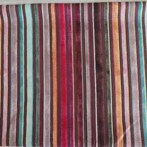 Puede incluir: Una tela con un patr&oacute;n de rayas en varios colores, incluyendo marr&oacute;n, naranja, rojo, azul, verde y amarillo. Las rayas son verticales y est&aacute;n espaciadas uniformemente.