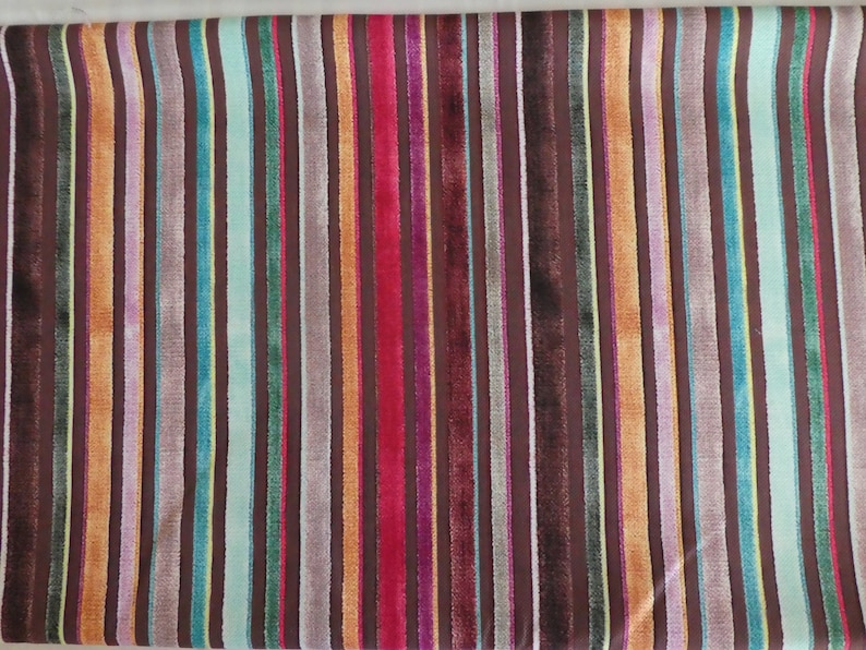 Puede incluir: Una tela con un patr&oacute;n de rayas en varios colores, incluyendo marr&oacute;n, naranja, rojo, azul, verde y amarillo. Las rayas son verticales y est&aacute;n espaciadas uniformemente.