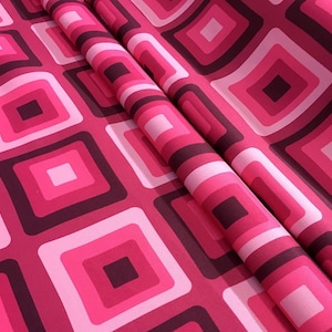 Puede incluir: Tela geométrica rosa y marrón con un patrón repetitivo de cuadrados dentro de cuadrados.