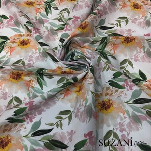 May include: White cotton fabric with a watercolor floral print featuring pink and orange flowers with yellow centers and green leaves. The fabric has the text "SUZANI Cotton" in the bottom right corner.