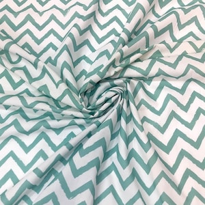 May include: White fabric with a teal chevron pattern. The fabric is folded and textured.