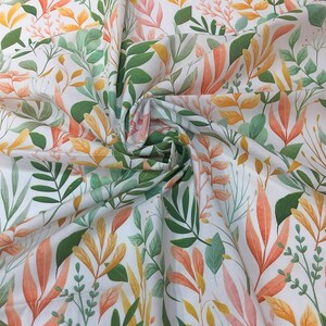 May include: White fabric with a repeating pattern of orange, yellow, and green leaves. The fabric is folded in the center.