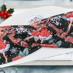 May include: A black and red Christmas themed headband with a girl in a red dress and the text "I Want It For Christmas".