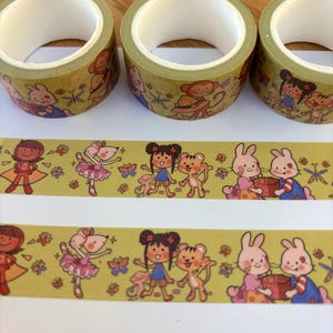 May include: Three rolls of decorative washi tape featuring cartoon characters like bunnies, monkeys, and girls. The tape has a light green background with colorful illustrations. The tape is designed for crafts and scrapbooking.