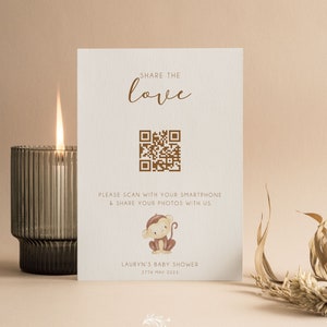 May include: A white card with a brown monkey illustration and a QR code. The text on the card reads "Share the love", "Please scan with your smartphone & share your photos with us", "Lauryn's Baby Shower", "27th May 2023", and "Full & Love".