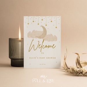 K&ouml;nnte beinhalten: Eine wei&szlig;e Karte mit goldener Schrift und einer Aquarell-Illustration eines Halbmondes und Wolken. Der Text lautet "Willkommen zu Ellies Baby Shower 25.06.23".
