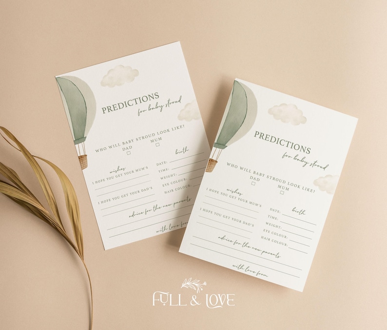 May include: Two baby shower prediction cards with a hot air balloon and cloud design. The cards have prompts for guests to fill out, including predictions for the baby's appearance and advice for the parents. The cards are on a neutral background.