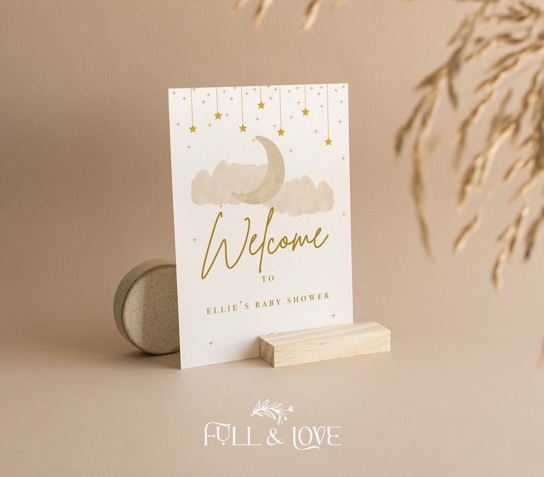 K&ouml;nnte beinhalten: Eine wei&szlig;e Karte mit goldener Schrift und einem goldenen Halbmond- und Sternenmuster. Die Karte lautet "Willkommen zu Ellies Babyparty".