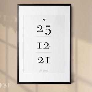 May include: A black framed print with a white background and black text. The text reads "25", "12", "21", and "Amy & Luke".