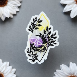 May include: A sticker featuring a purple, yellow, and white crystal with a black crescent moon and black floral accents.
