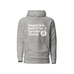 Puede incluir: Una sudadera con capucha gris con una impresión blanca que dice "Veggie Sub, Sweet Tea & Sprinkle Cookie." La impresión también incluye una letra "P" blanca en un círculo.