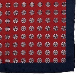 May include: A red pocket square with a navy blue border and a white and blue patterned design.