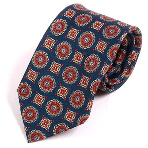 May include: A navy blue tie featuring a repeating pattern of red, yellow, and white circular and square designs. The tie is knotted, displaying the detailed pattern and colour scheme.