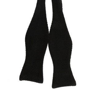 May include: A black knitted bow tie. The bow tie is made of a soft, textured fabric.