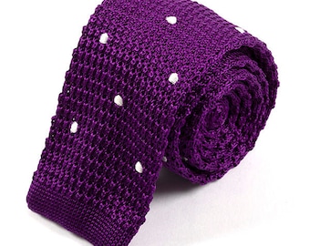 May include: A rolled-up, knitted purple tie with white polka dots. The tie is made of a textured material and is displayed on a white background. The tie is a classic accessory for formal or business attire.