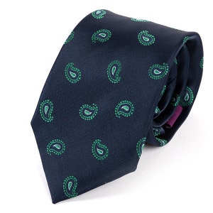 May include: A navy blue tie featuring a repeating paisley design in green and white. The tie is rolled, revealing a purple label on the reverse. The fabric appears smooth, possibly silk. A classic accessory.