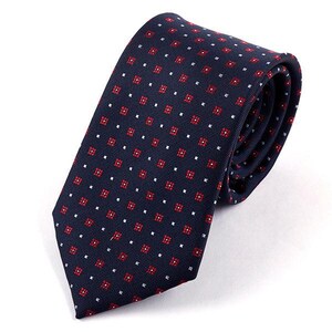 Peut inclure: Une cravate bleu marine avec un motif géométrique rouge et blanc. La cravate est en matière soyeuse et a un design classique.