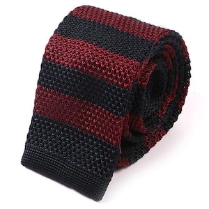 May include: A knitted tie with burgundy and navy blue stripes. The tie is made of a soft, textured material.
