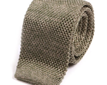 May include: A green knitted tie with a textured pattern. The tie is rolled up and ready to be worn.