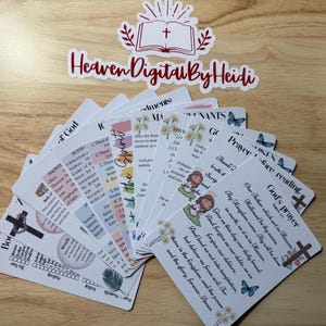 Może przedstawiać: Zbi&oacute;r białych kart z tekstem i ilustracjami religijnymi, w tym krzyżami, motylami i kwiatowymi wzorami. Karty ułożone są w wachlarz na drewnianej powierzchni, z widocznym tekstem "Heaven Digital By Heidi".