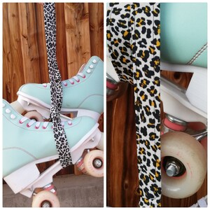 May include: A pair of light blue roller skates with black wheels and a leopard print strap. The skates are hanging from a wooden wall.