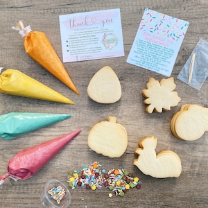 May include: A DIY cookie decorating kit with four different cookie shapes: a pumpkin, a leaf, an acorn, and a squirrel. The kit includes four piping bags filled with different colored icing, a small container of sprinkles, and a set of toothpicks. The kit also includes instructions on how to decorate the cookies.