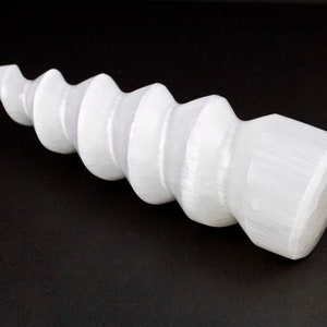 Puede incluir: Cristal de selenita blanco tallado en forma de espiral. El cristal es liso y pulido, con una superficie ligeramente texturizada.