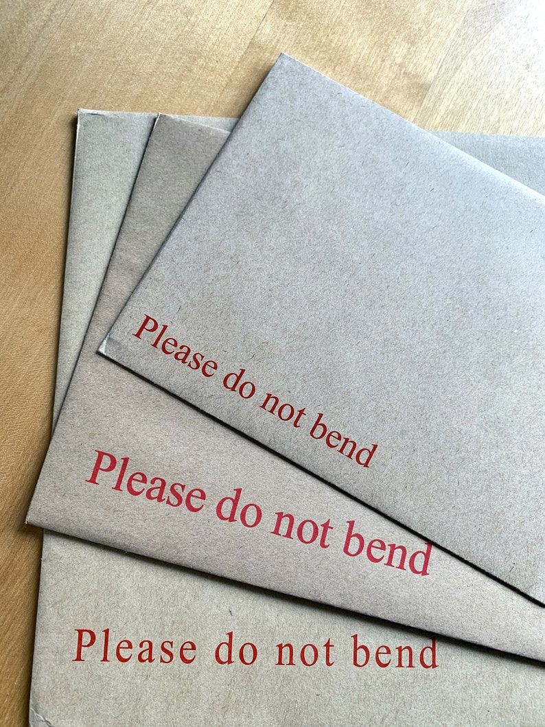 Op de afbeelding: Drie bruine enveloppen gestapeld op elkaar. De bovenste envelop heeft de tekst "Please do not bend" in het rood gedrukt. De middelste envelop heeft dezelfde tekst in het rood gedrukt. De onderste envelop heeft dezelfde tekst in het rood gedrukt.