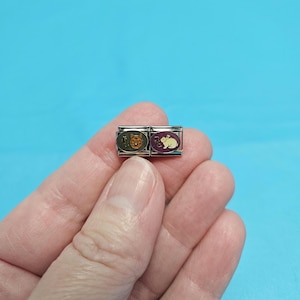 May include: Two silver charm bracelets with animal designs. The left charm features a brown bear with a yellow background. The right charm features a white rabbit with a purple background.