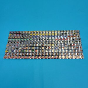 May include: A collection of colorful charm bracelets with various designs, including shoes, hats, and other accessories. The charms are arranged in rows on a blue background.