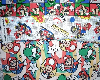 May include: A multi-layered fabric featuring three distinct patterns. The top layer shows a grid of Mario and Luigi characters. The middle layer is white with comic-style graphics, karts, and the text VROOM. The bottom layer displays Mario, Toad, and Yoshi with stars and rainbows.