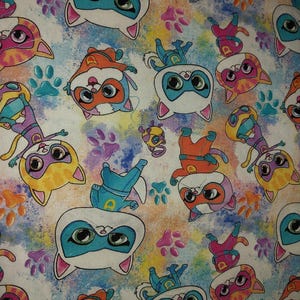 Op de afbeelding: Een witte achtergrond met een kleurrijk patroon van cartoonkatten die superheldenpakken dragen. De katten staan in verschillende poses en hebben verschillende gekleurde pakken. De achtergrond is een aquarelachtig ontwerp met kleurspatten.