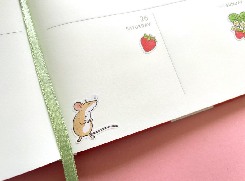 May include: A brown mouse sticker with a white background. The mouse is standing on its hind legs with its front paws together. The mouse is looking to the right.