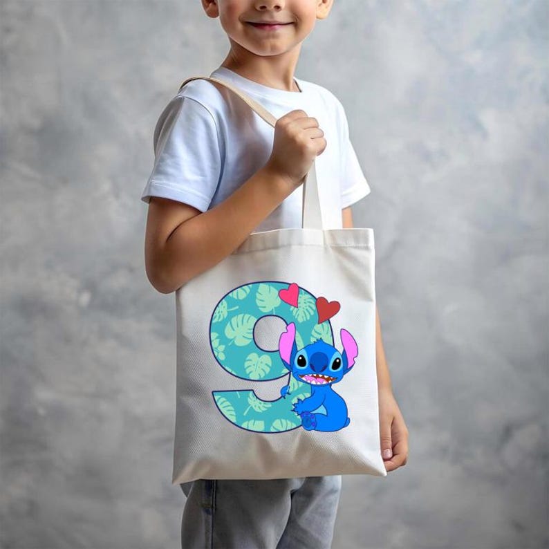 May include: A white tote bag with a blue Stitch character holding a green number nine with pink hearts. The number nine is made up of green tropical leaves.