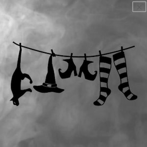 Puede incluir: Silueta negra de un gato colgado boca abajo en un tendedero junto a un sombrero de bruja, zapatos y calcetines a rayas. Los objetos están sujetos con pinzas, creando una imagen de Halloween.
